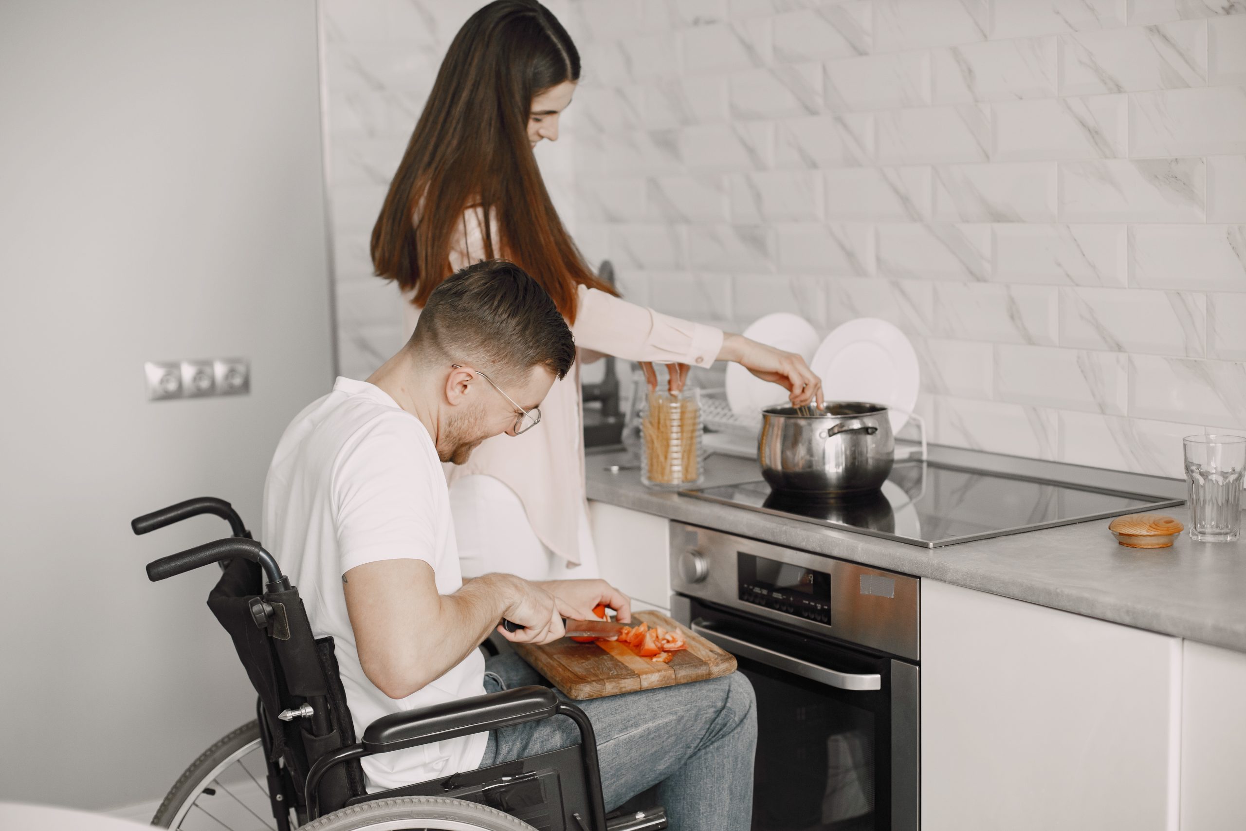 Disabled Young Man in Wheelchair Preparing Food In Kitchen